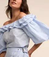 Blusa con escote hombro a hombro, confeccionada en tricolina con estampa rayada, volados en el escote y mangas cortas amplias.