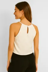 Top color crema de breteles finos, corte al cuerpo y cuello halter.