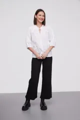 Blusa blanca de algodón con escote en V con lazos, mangas 3/4 abullonadas y corte holgado.