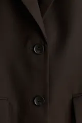 Blazer marrón oscuro de corte recto, con solapas de muesca, hombreras y bolsillos ribeteados con solapa.
