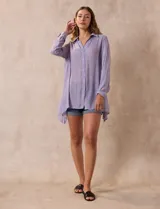 Camisa color beige claro, de corte recto y mangas 3/4 con botón para sujetar.