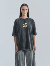 Remera negra con efecto nevado, corte oversize y estampado de Mickey Mouse sobre una patineta.