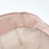 Gorro tipo bucket de tela de algodón color beige con rayas verticales blancas.