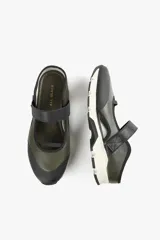 Zapato de cuero sintético color verde oliva y negro, con suela track blanca y tira de velcro en el empeine.