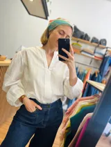 Camisa blanca amplia con escote en V y mangas largas abuchonadas, confeccionada en broderie.