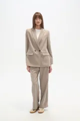 Blazer cruzado de color beige claro, con cuello solapa, dos botones frontales y bolsillos con tapa.