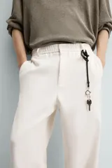 Pantalón de vestir color blanco hueso, de corte recto y tiro medio, con cintura elástica y cierre frontal de botón y cremallera. Presenta bolsillos frontales y bolsillos traseros de vivo.