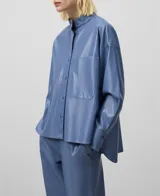 Sobrecamisa azul de cuero sintético con cuello mao, cierre frontal con botones, bolsillo de parche en el pecho, mangas largas y corte asimétrico.