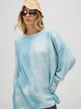 Buzo de algodón con efecto tie-dye en tonos celeste y blanco, de corte holgado y largo por debajo de la cintura, con puños acanalados.