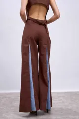 Pantalón ancho marrón con aberturas frontales que revelan un forro o panel interior de tela celeste. El pantalón se combina con un top a juego, creando un conjunto de dos piezas.