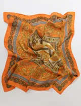 Pañuelo cuadrado de satén color naranja con estampado de motivos florales y grecas en tonos dorados, marrones y beige.