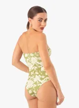 Traje de baño enterizo verde con estampado floral blanco, escote strapless con detalle de nudo y aberturas en la zona del abdomen.