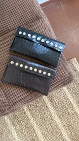 Billetera de ecocuero con textura símil cocodrilo, cierre con botón a presión, tres compartimentos para billetes, seis compartimentos para tarjetas (con capacidad para 12 tarjetas) y sobre de regalo para monedas.