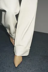 Botín de cuero color beige con punta fina y tacón kitten. Cierre con cremallera lateral.