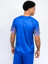 Remera deportiva azul con el escudo del Club Nacional de Football en el pecho y diseño de cuadros rojos y blancos en las mangas.