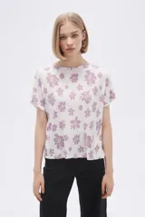 Remera blanca con estampado floral en color lila, de corte holgado y mangas cortas.
