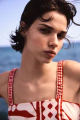 Top cropped de popelina de algodón color blanco con estampado floral y geométrico en rojo. Tiene escote recto, breteles elásticos y espalda fruncida.