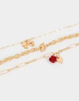Set de tres collares dorados con diferentes cadenas de eslabones y dijes metálicos: cadena gruesa con cierre de barra, cadena con eslabones rectangulares y dije de rosa roja, y cadena con dije de moño.