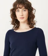 Suéter de punto color verde, con cuello barco, mangas largas y textura acanalada.