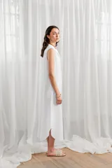 Vestido túnica midi sin mangas, color blanco, con cuello camisero y cierre frontal con botones.