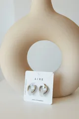 Aros de acero quirúrgico hipoalergénico con forma de argolla plateada y dije circular colgante de piedra natural color azul.