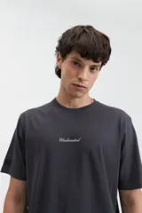 Remera color crema de manga corta con estampado de águilas y texto distorsionado en la espalda. Corte regular.