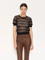 Top de encaje negro con cuello redondo y mangas cortas con volados.
