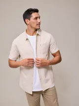 Camisa de manga corta color beige con rayas verticales y bolsillo en el pecho.