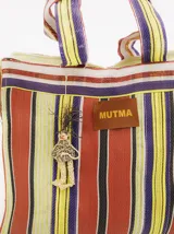 Bolso playero tipo tote bag a rayas horizontales en tonos naranja, amarillo, blanco y violeta. Tiene doble asa corta y cierre superior con cremallera. Incluye un dije colgante y una etiqueta de cuero sintético con el logo de la marca.