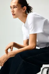 Remera blanca de corte recto en punto suave de algodón con cuello redondo ribeteado y hombros ligeramente caídos.