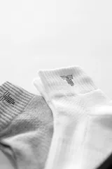 Pack de tres pares de medias de caña media, color negro, blanco y gris, con logo en el tobillo.