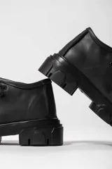 Bota acordonada color suela, con suela track y cordones color naranja.