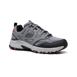 Championes Skechers Hillcrest Vast Adventure, color gris con detalles en negro y rojo. Capellada de cuero sintético y malla, entresuela moteada con absorción de impactos, plantilla Memory Foam y suela de goma flexible.