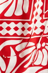 Short de tela color blanco con estampado de flores rojas, cintura elástica con cordón ajustable y bolsillos laterales.