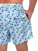 Short de baño celeste con estampado de ballenas en azul y gris. Tiene cintura elástica con cordón ajustable y bolsillos laterales.