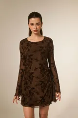 Vestido mini de poliéster color marrón, con estampado floral en negro, cuello bote, mangas largas y fruncido lateral.