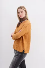 Sweater color mostaza de tejido de punto con detalle de lentejuelas integradas al hilado, calce holgado y mangas largas.