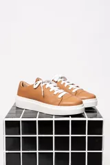 Zapatilla de cuero color marrón con diseño minimalista y cordones.
