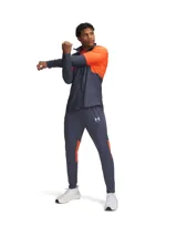 Pantalón deportivo Under Armour Challenger de hombre, color gris con detalles en naranja y logo de la marca en blanco.