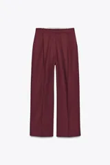 Pantalón de vestir color borgoña, de tiro alto y pierna ancha, con bolsillos laterales y cierre frontal con cremallera y ganchos metálicos.