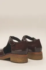 Zapato guillermina de cuero vacuno charol color negro, con suela de goma color marrón.