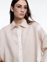 Camisa de lino color negro con silueta amplia y mangas 3/4. Diseño con tiras de color blanco en contraste en la cartera, mangas y cuerpo. Tiene tajos laterales y ruedo irregular en el frente.