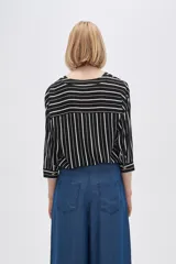 Camisa holgada de viscosa con estampado de rayas verticales en blanco y negro, cuello en V y mangas 3/4 con detalle de botones.