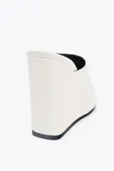 Zapato de mujer tipo mule, color blanco, con punta fina y tacón de cuña.