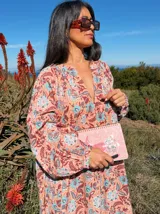Vestido largo de corte amplio con estampado floral en tonos rosa, marrón y celeste. Tiene escote en V y mangas largas abullonadas.
