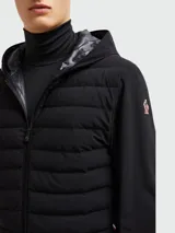 Campera acolchada negra con capucha, cierre frontal con cremallera, mangas largas y bolsillos laterales con cremallera. Detalle de logo en la capucha. Marca Moncler Grenoble.