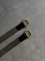 Cinturón negro de cuero ecológico con hebilla dorada y múltiples ojales dorados.