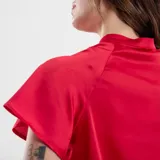 Blusa color azul con diseño de cuello alto y detalles drapeados en la parte delantera.