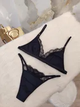 Conjunto de lencería negro, compuesto por un corpiño triangular de algodón con detalles de encaje y una tanga de algodón con detalles de encaje.