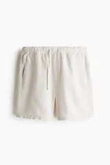 Short color crema en tejido liviano de algodón y viscosa. Modelo con cierre decorativo, elástico revestido con cordón para ajustar en la cintura, bolsillos al bies y bolsillo insertado atrás. Corte relajado para una silueta casual.